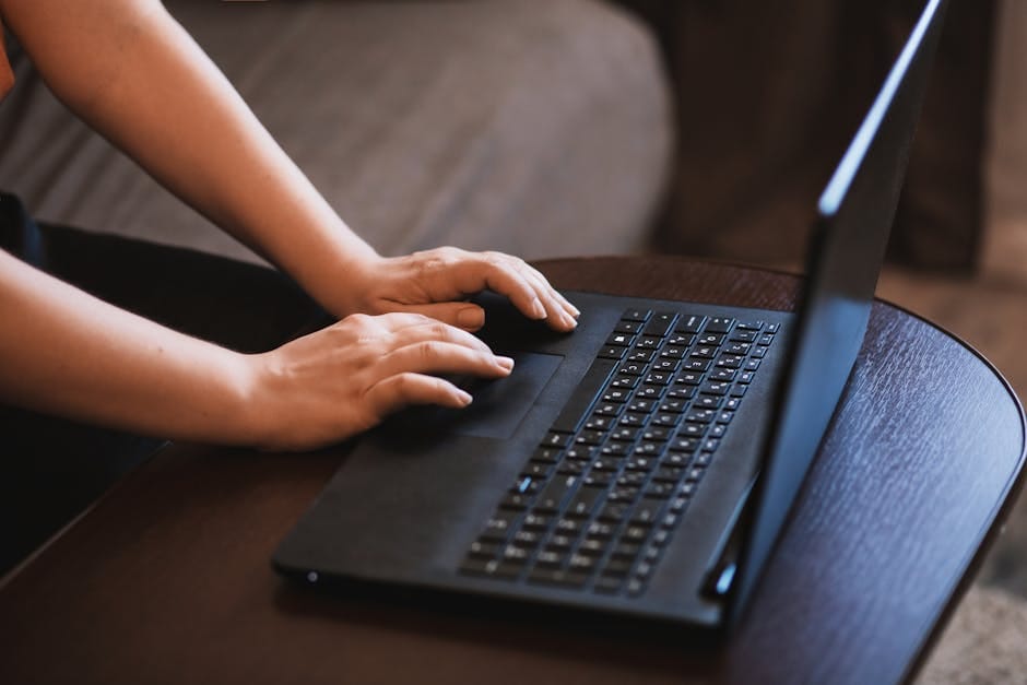 Hands typing on a laptop in a modern workspace.